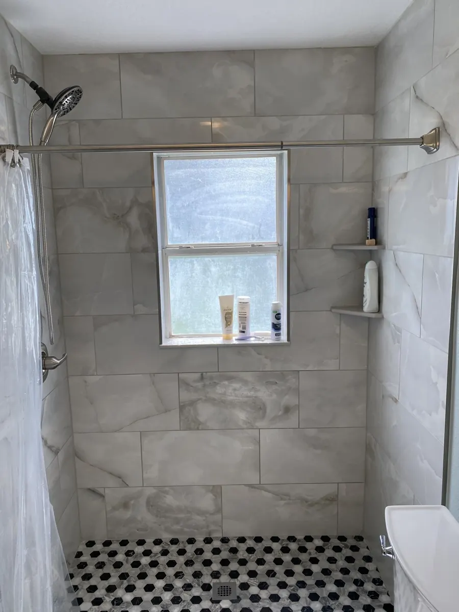 Gray tile shower with mosaic flooring